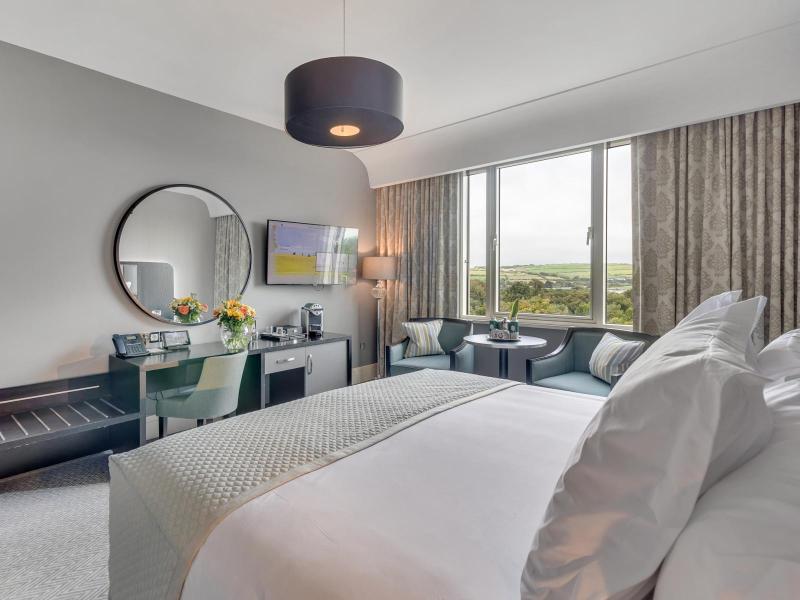 Deluxe King room image - point of view of bed looking towards window and mirror