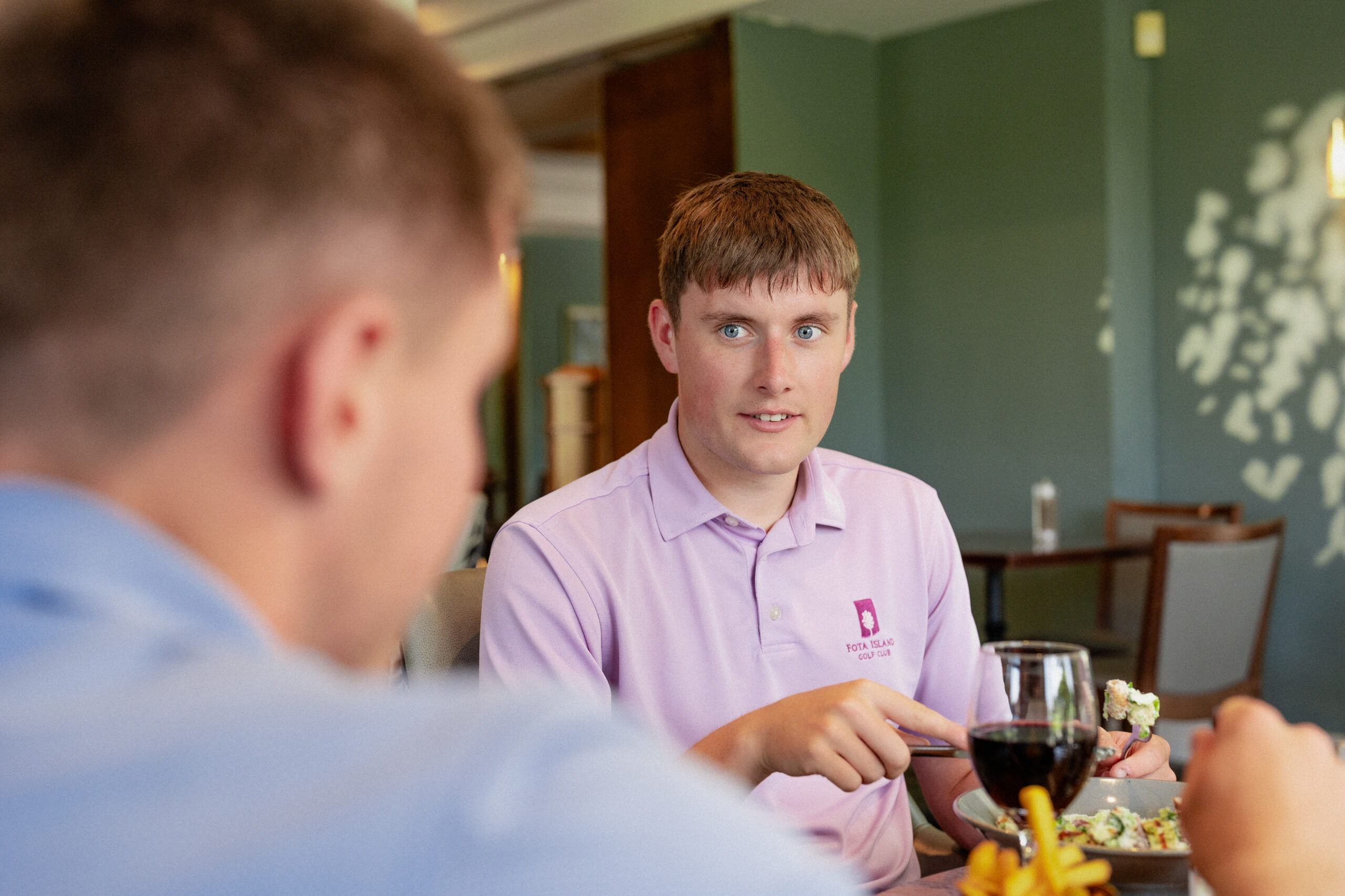 Golfer listening to other golfer at dinner table at The Clubhouse