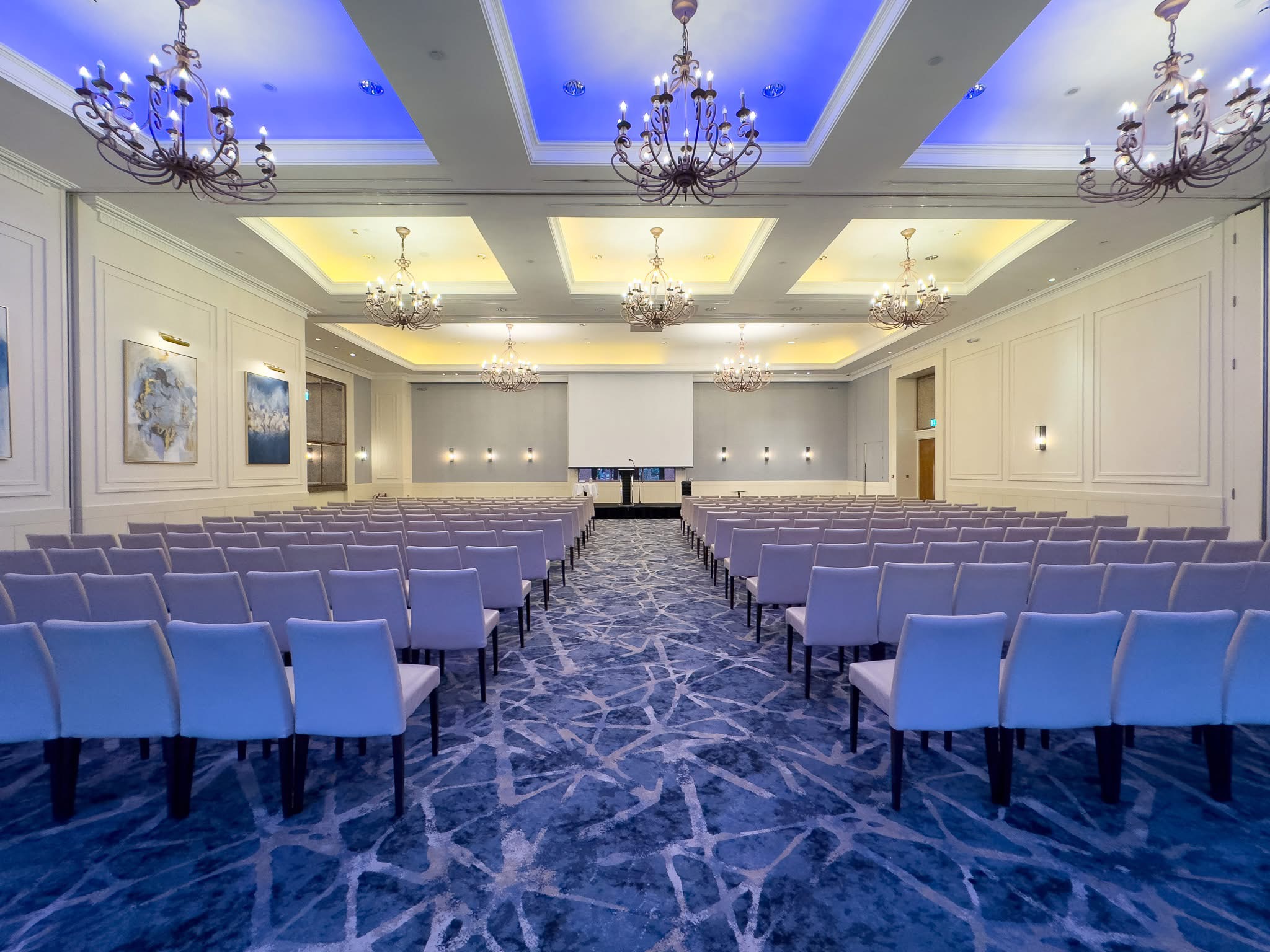 Conference in Smith Barry Suite set up shot down the middle of the aisle with projector screen in view