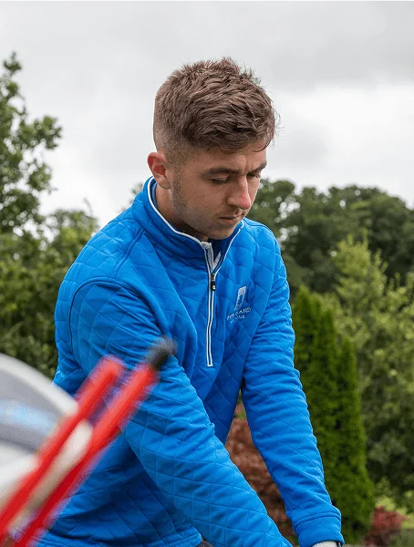 Golfer in blue zip preparing to swing, shot through golf clubs at Fota Island Resort