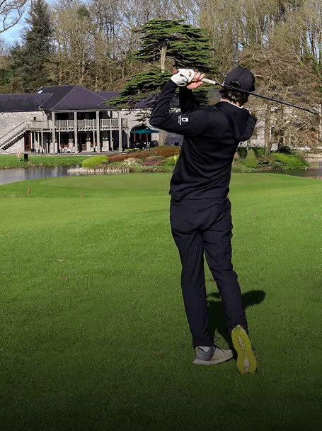 Golfer playing an iron into the 18th hole with shot of clubhouse in the background