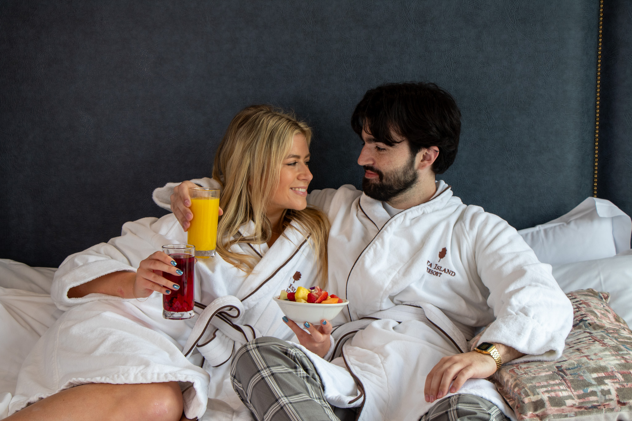 Couple in bedroom in robes enjoying breakfast in bed