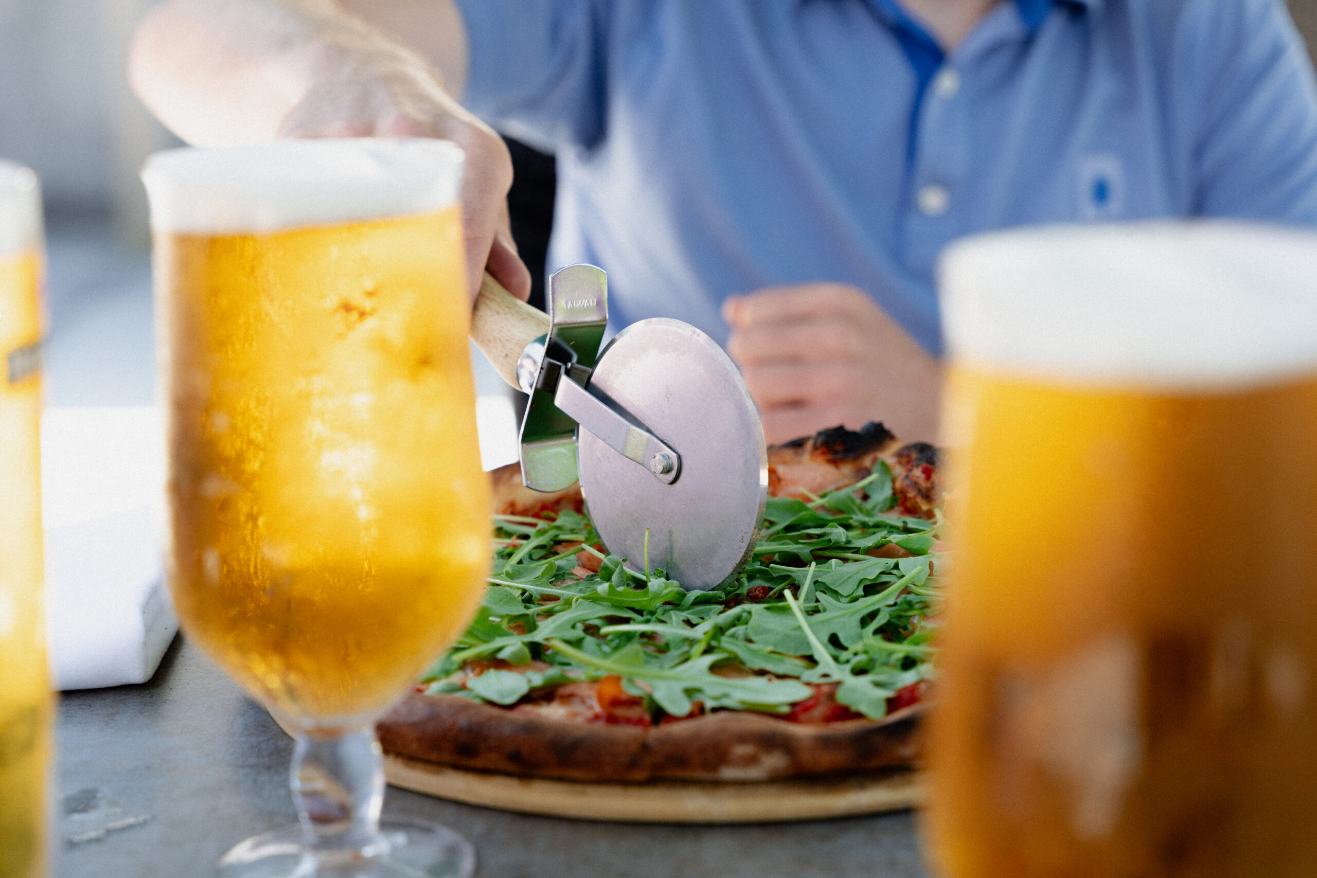 Up close image of beers and pizza being cut