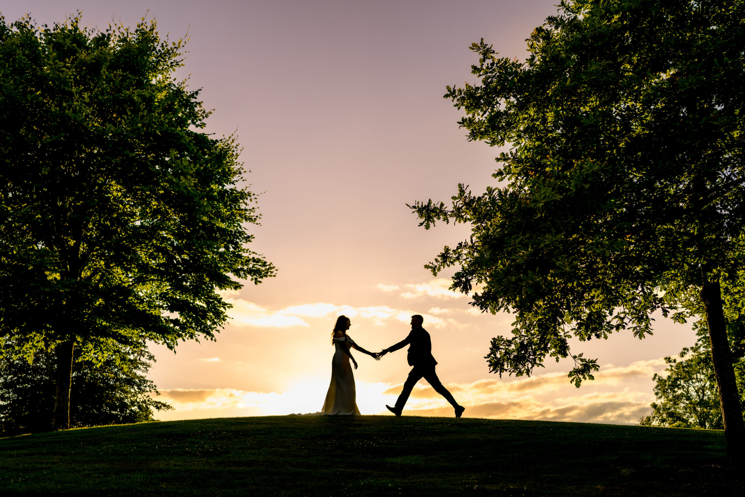Silhouette of wedding couple on golf course in sunlight