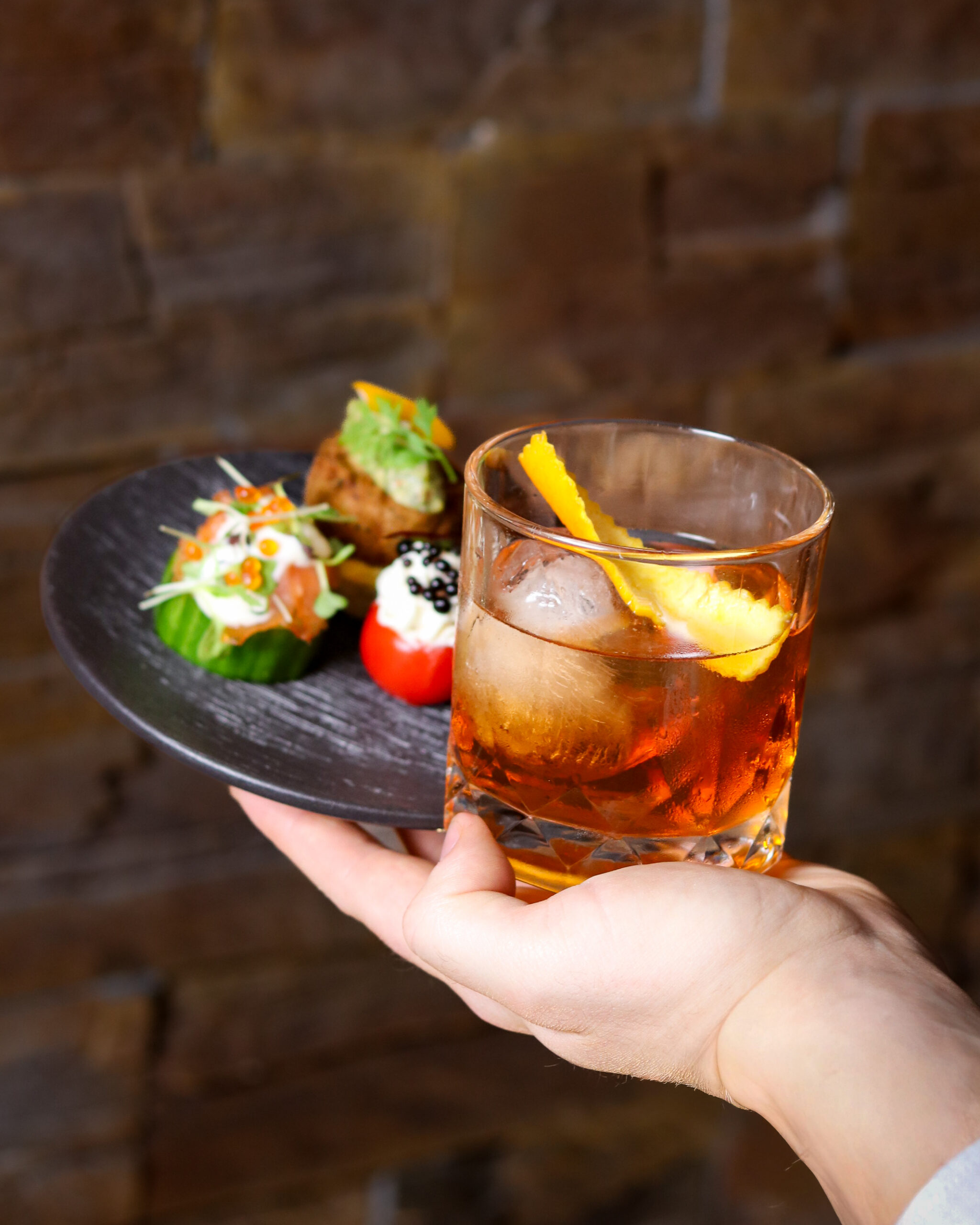 Cocktail and sharing plate selection held in one hand at The Cove