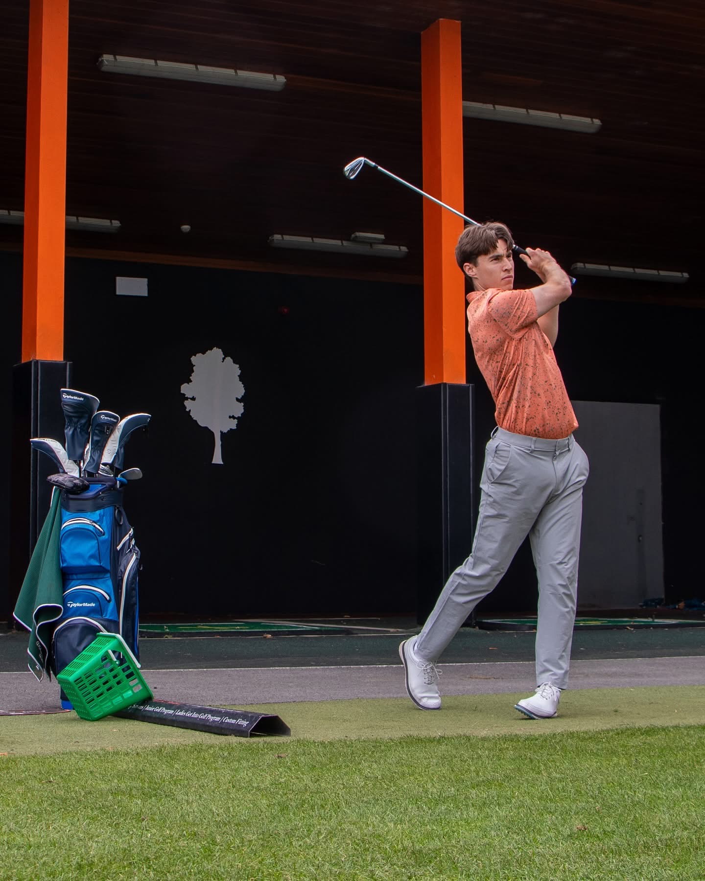 Golfer swinging a club at Fota Island Golf Academy with the Fota 'tree' logo in the background